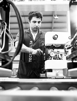 Técnico numa fábrica a operar máquina industrial, visto entre estruturas metálicas